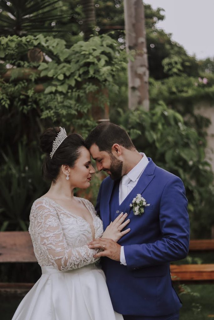 Bride and groom share an intimate moment amidst greenery in an elegant garden setting.