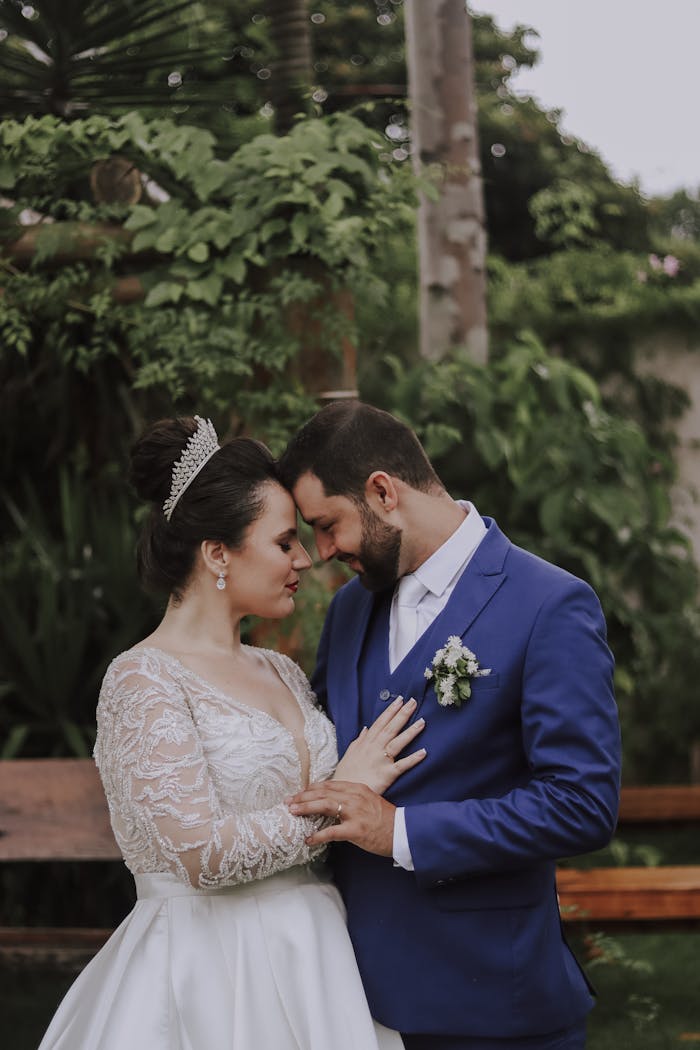 Bride and groom share an intimate moment amidst greenery in an elegant garden setting.